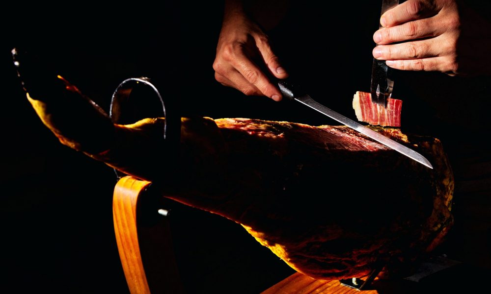 Gastronomy and food in Spain Close-up detail of master Iberian ham cutter on dark background.